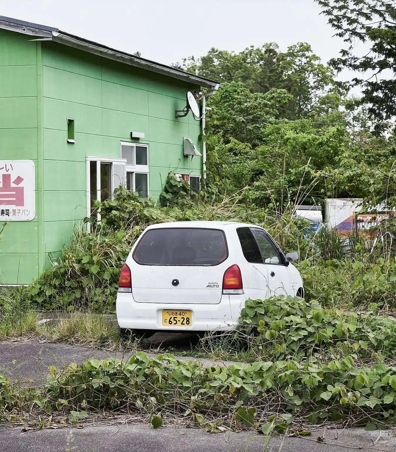 A photograph of a car parked in the village of Fukushima
