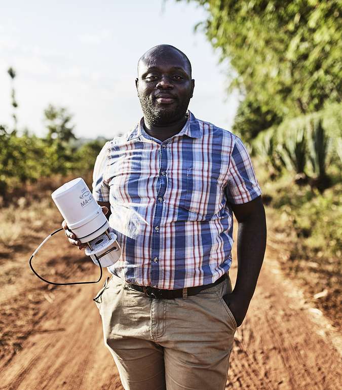 A photograph of an African citizen standing in a field holding ATMOS 41 weather station
