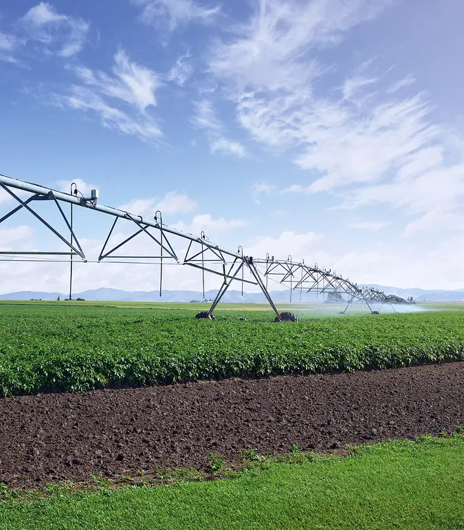 A photograph of an irrigation pivot watering a crop in a field