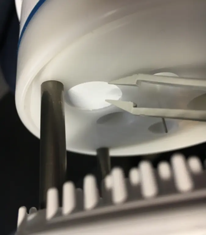 Photo of underside of ATMOS 41 with tweezers pointing to teflon circle