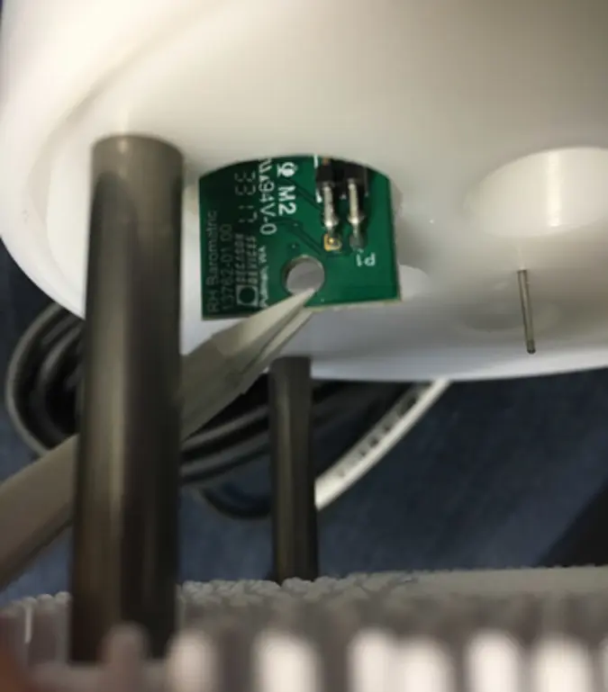 Photo of underside of ATMOS 41 with tweezers removing daughter board