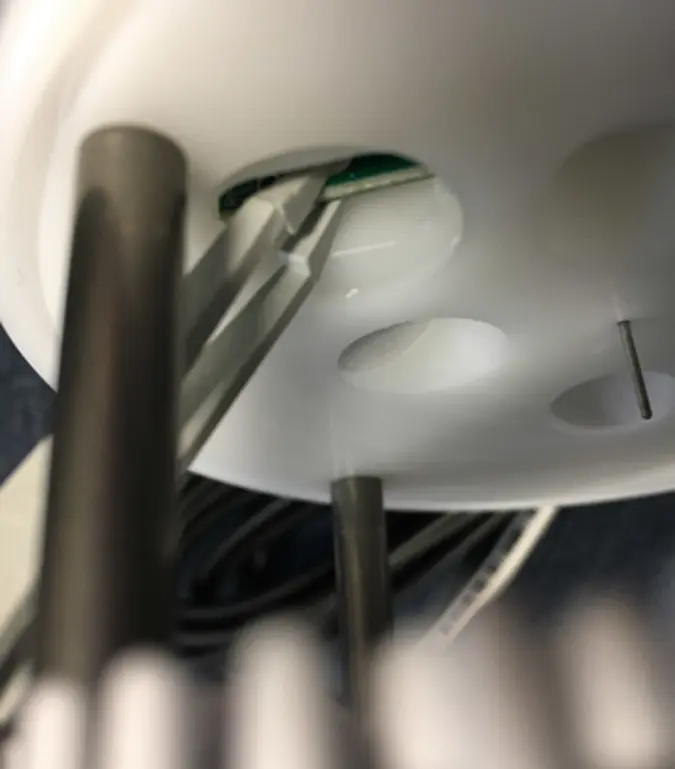 Photo of underside of ATMOS 41 with tweezers grasping daughter board