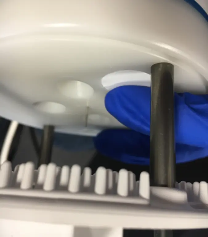 A photograph of a gloved hand pushing in the new Teflon disc