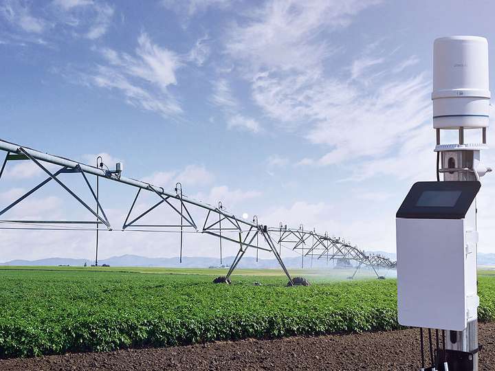 A central pivot irrigation system watering a crop in the background with a ZL6 Data Logger and ATMOS 41 weather station in the foreground