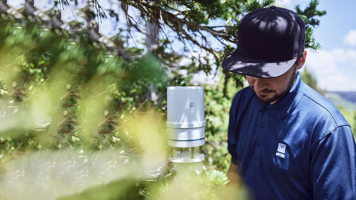 A researcher installing an ATMOS 41 all-in-one weather station in the field