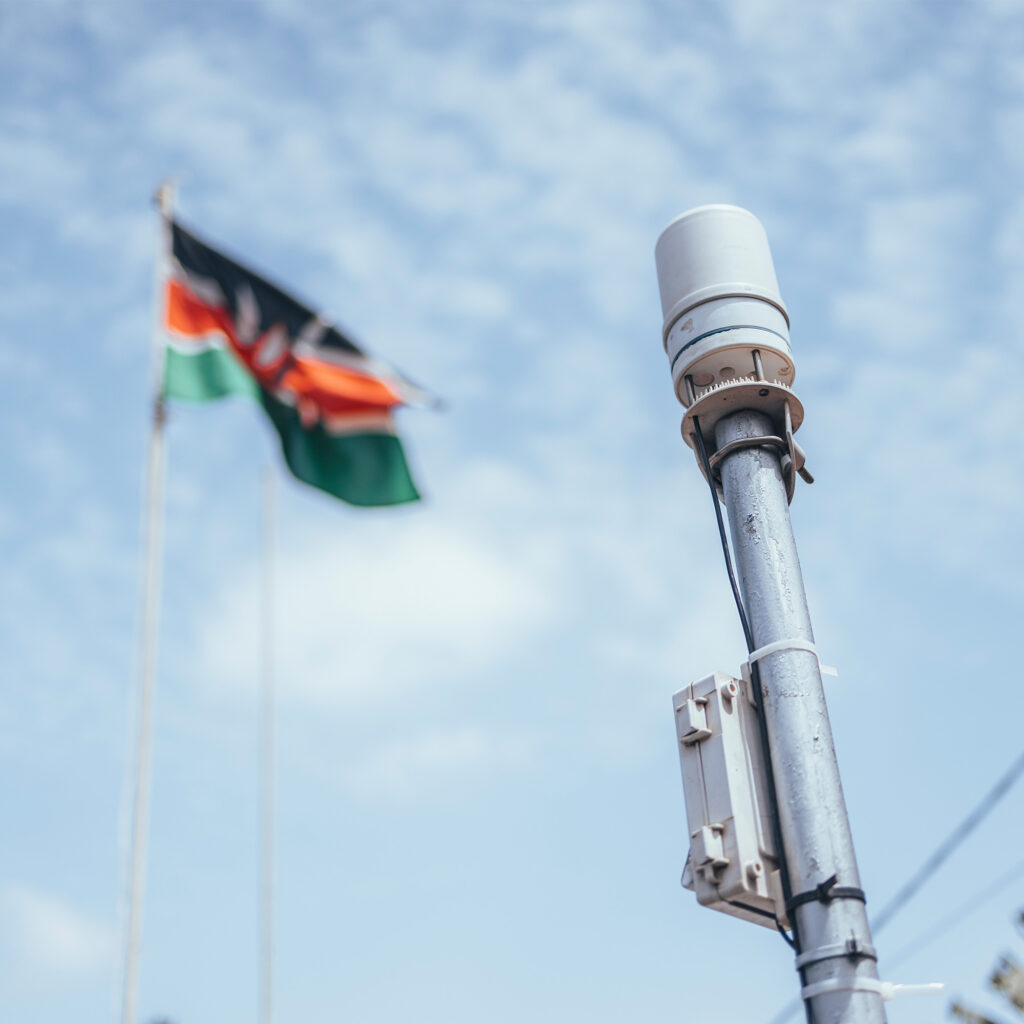 A photograph of an ATMOS 41 all-in-one weather station on a pole with a ZL6 data logger with the Kenyan flag flying in the background