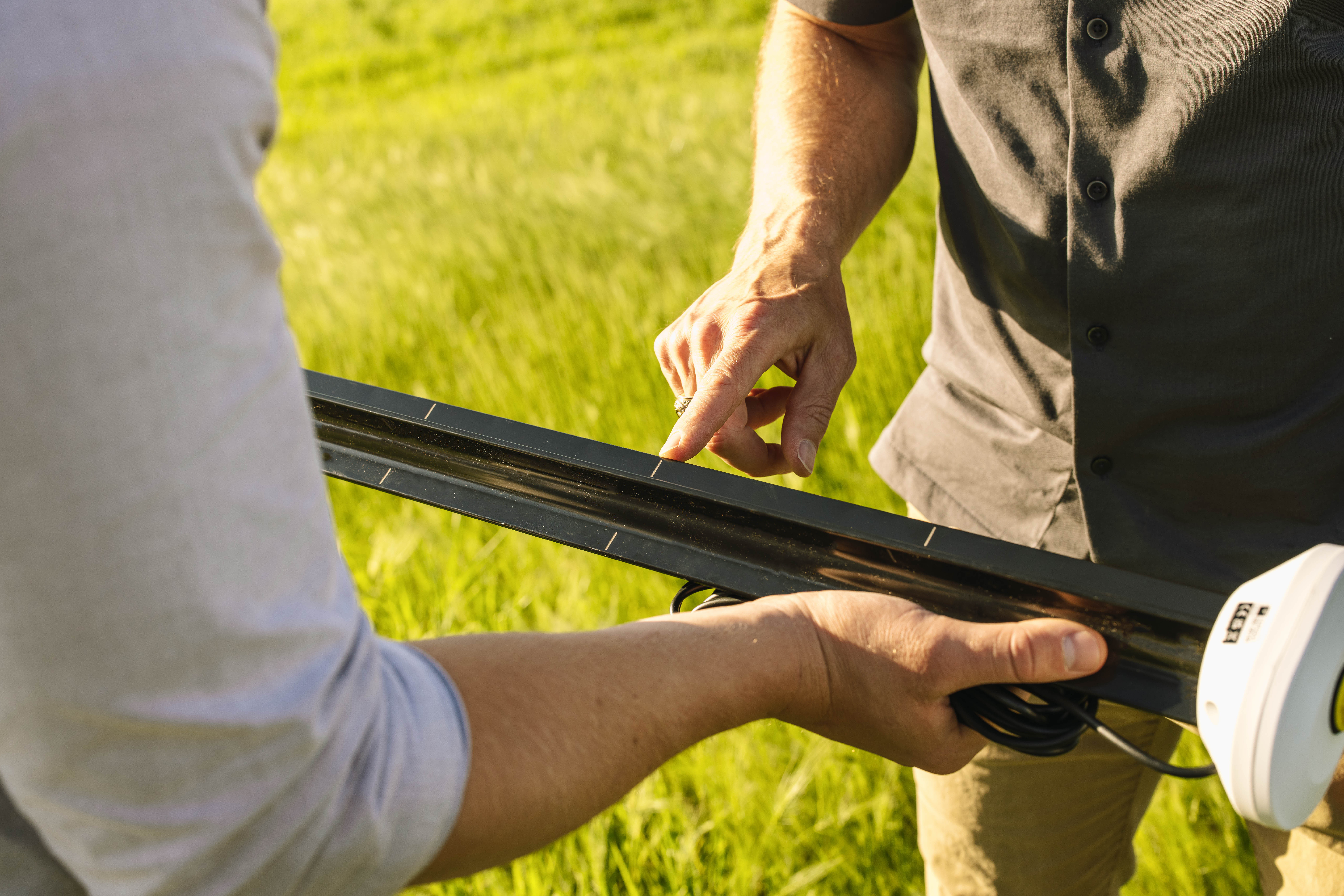 A photograph of two researchers examining a TEROS 54 while standing in a wheat field
